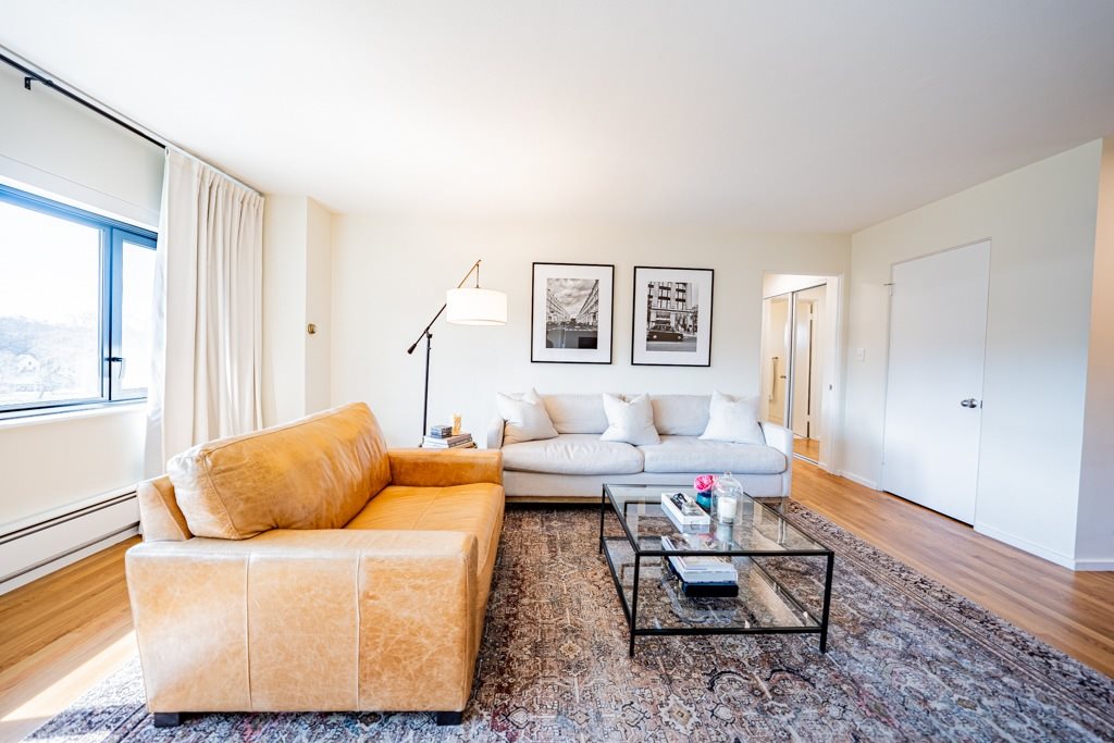 A living room with a tan couch and a white couch.